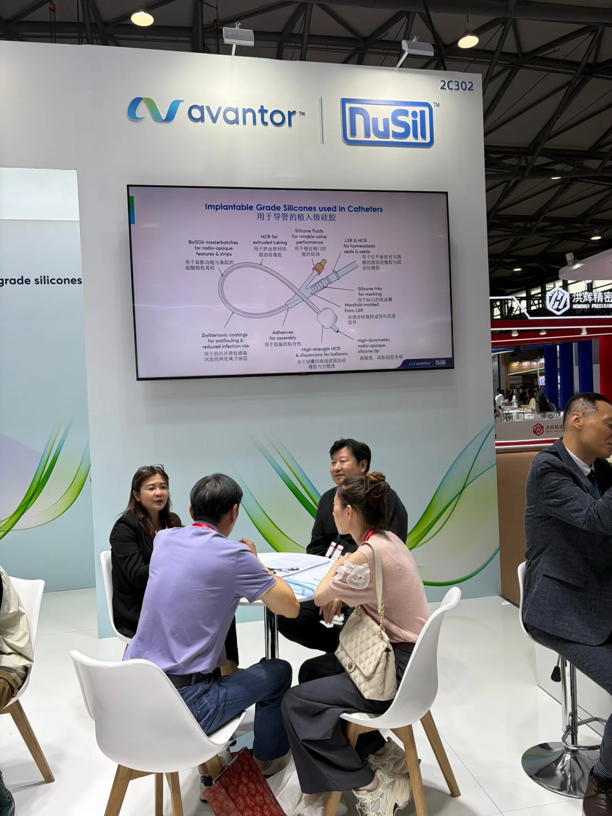 Visitors seated beneath an implant-grade silicone catheter application display at the Avantor NuSil exhibit